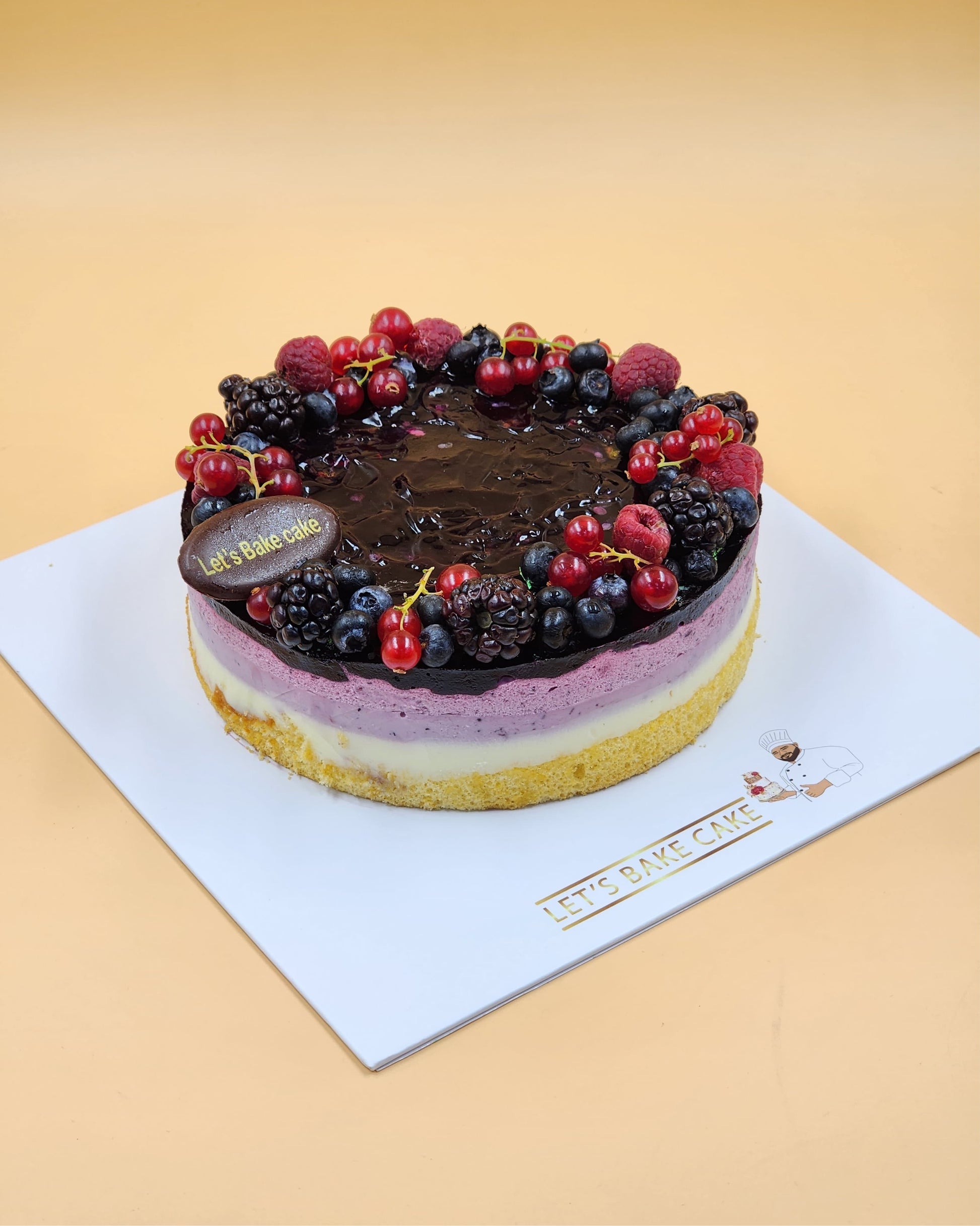 A luxury layered mixed berry mousse cake topped with fresh blackberries, raspberries, and red currants by Let's Bake Cake Abu Dhabi.