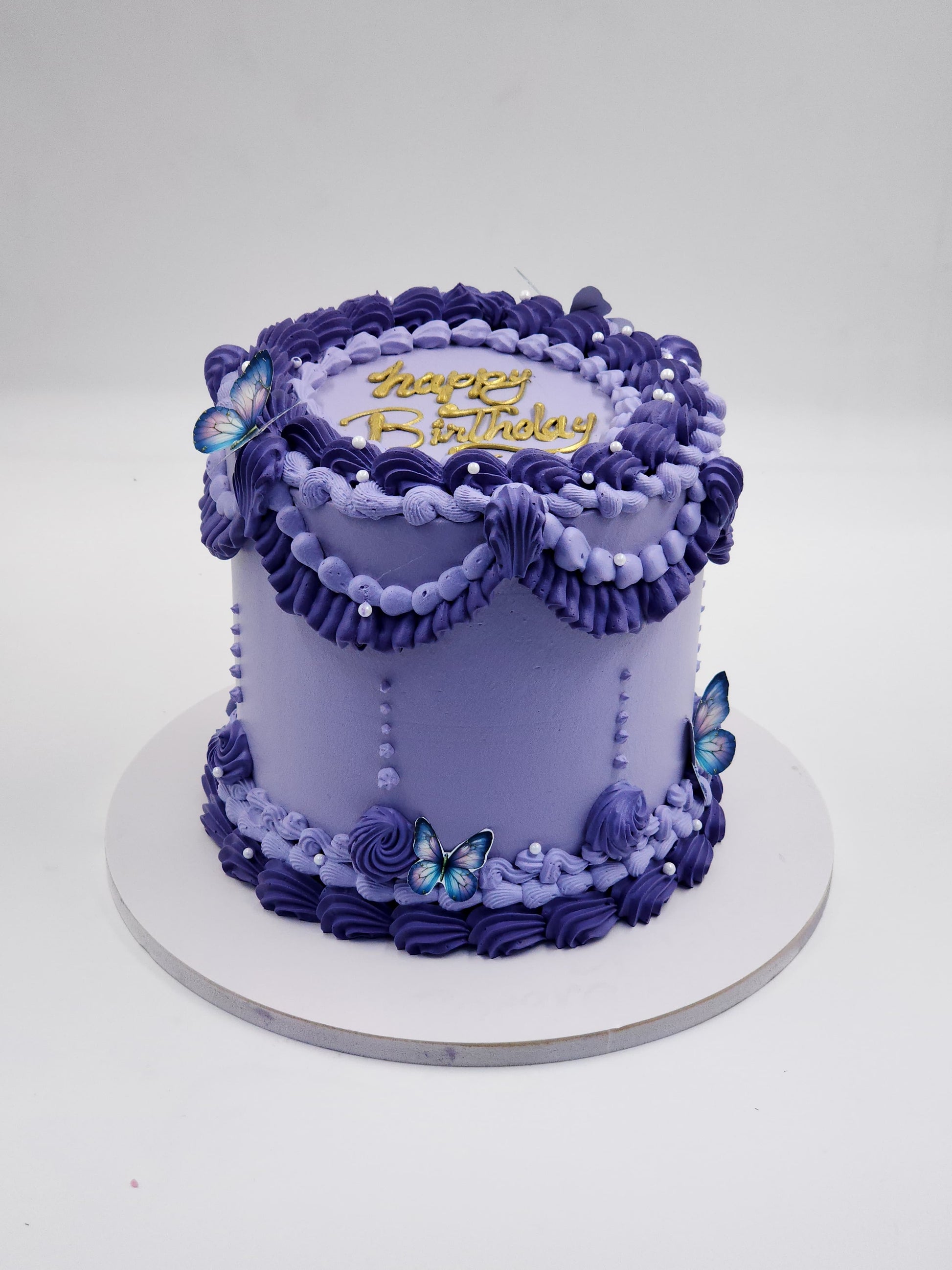 A luxury purple and lavender vintage Lambeth-style piped birthday cake with edible butterflies and gold topper by Let's Bake Cake Abu Dhabi.