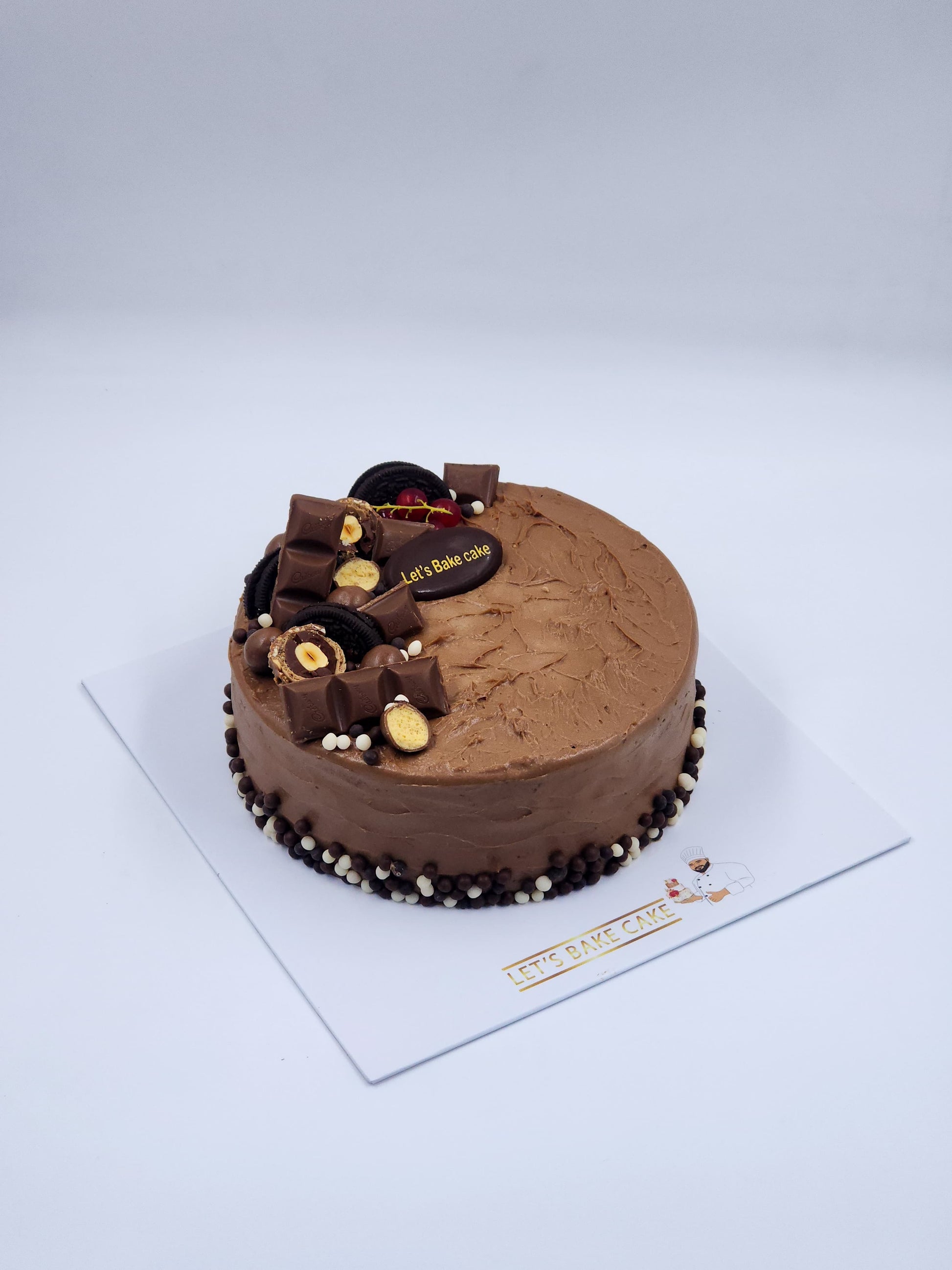 A luxury chocolate birthday cake loaded with Kinder bars, Oreos, and chocolate pearls by Let's Bake Cake Abu Dhabi.